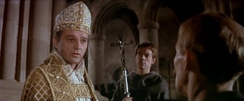 Movie still from “Becket” (1964), directed by Peter Glenville – A man holding a crucifix in front of another man; Close Up shot, Over the shoulder angle