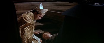 Movie still from “Becket” (1964), directed by Peter Glenville – A man laying on the ground next to another man wearing a crown; Medium shot, High angle