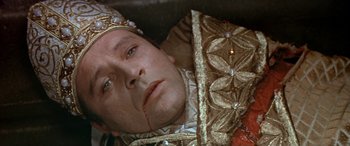 Movie still from “Becket” (1964), directed by Peter Glenville – A person wearing a crown with blood on his face; Close Up shot, Overhead angle