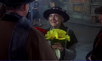 Movie still from “Bedknobs and Broomsticks” (1971), directed by Ward Kimball – An older woman holding a bunch of yellow flowers; Medium shot, Over the shoulder angle