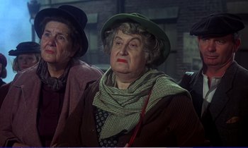 Movie still from “Bedknobs and Broomsticks” (1971), directed by Ward Kimball – Two older women sitting next to each other wearing hats; Medium shot, Low angle