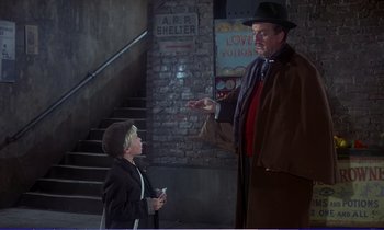Movie still from “Bedknobs and Broomsticks” (1971), directed by Ward Kimball – A man and a boy are talking to each other in front of a brick wall; Medium shot, Over the shoulder angle