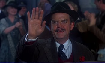 Movie still from “Bedknobs and Broomsticks” (1971), directed by Ward Kimball – A man wearing a suit and a hat waving at a crowd; Close Up shot, Low angle