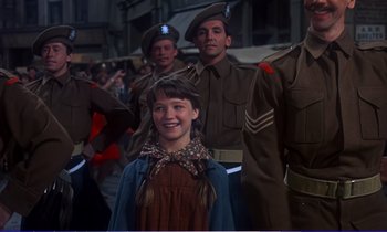 Movie still from “Bedknobs and Broomsticks” (1971), directed by Ward Kimball – A group of men and a girl in uniform; Medium shot, Over the shoulder angle