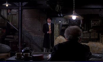 Movie still from “Bedknobs and Broomsticks” (1971), directed by Ward Kimball – A man in a suit and hat standing in front of an audience; Wide shot, Over the shoulder angle