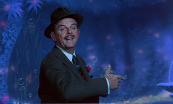 Movie still from “Bedknobs and Broomsticks” (1971), directed by Ward Kimball – A man in a suit and hat is holding a cigarette; Medium shot, Low angle
