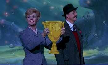 Movie still from “Bedknobs and Broomsticks” (1971), directed by Ward Kimball – A man and a woman holding up a trophy; Medium shot, Low angle