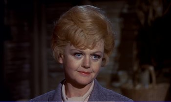 Movie still from “Bedknobs and Broomsticks” (1971), directed by Ward Kimball – An older woman with blonde hair wearing a purple jacket; Close Up shot, Over the shoulder angle