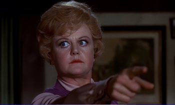 Movie still from “Bedknobs and Broomsticks” (1971), directed by Ward Kimball – An older woman is holding a gun in her hand; Close Up shot, Over the shoulder angle