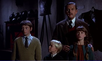 Movie still from “Bedknobs and Broomsticks” (1971), directed by Ward Kimball – A group of people standing next to each other in a room; Medium shot, Low angle