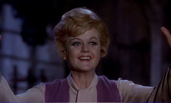 Movie still from “Bedknobs and Broomsticks” (1971), directed by Ward Kimball – An older woman with blonde hair and blue eyes smiling; Close Up shot, Low angle