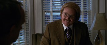 Movie still from “Bedtime Stories” (2008), directed by Adam Shankman – A man in a suit and tie smiling for the camera; Close Up shot, Over the shoulder angle