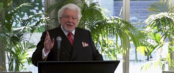 Movie still from “Bedtime Stories” (2008), directed by Adam Shankman – An older man wearing a suit and a red striped tie; Medium shot, Over the shoulder angle