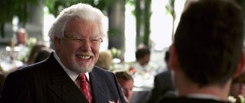Movie still from “Bedtime Stories” (2008), directed by Adam Shankman – An older man in a suit and tie smiling for the camera; Close Up shot, High angle