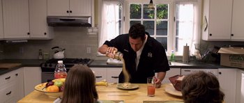 Movie still from “Bedtime Stories” (2008), directed by Adam Shankman – A man pouring sauce onto a plate on a table; Medium shot, High angle