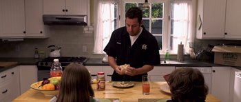 Movie still from “Bedtime Stories” (2008), directed by Adam Shankman – A man standing at a table with a plate in front of him; Medium shot, High angle