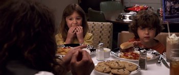 Movie still from “Bedtime Stories” (2008), directed by Adam Shankman – A girl eating cookies at a dinner table; Medium shot, High angle