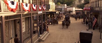 Movie still from “Bedtime Stories” (2008), directed by Adam Shankman – A group of people riding horses down a street; Extreme Wide shot, High angle