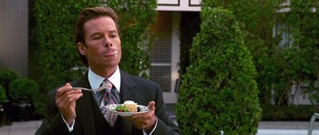 Movie still from “Bedtime Stories” (2008), directed by Adam Shankman – A man in a suit holding a plate of food in his hand; Close Up shot, Over the shoulder angle