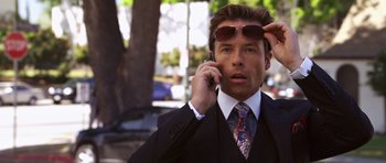 Movie still from “Bedtime Stories” (2008), directed by Adam Shankman – A man in a suit and sunglasses talking on a cell phone; Close Up shot, Over the shoulder angle