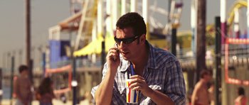 Movie still from “Bedtime Stories” (2008), directed by Adam Shankman – A man holding a drink while talking on a cell phone; Medium shot, High angle