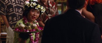 Movie still from “Bedtime Stories” (2008), directed by Adam Shankman – A woman wearing a lei and holding a tray of food; Close Up shot, Over the shoulder angle