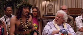 Movie still from “Bedtime Stories” (2008), directed by Adam Shankman – A man sitting next to a woman and a man with a flower in his hair; Medium shot, Over the shoulder angle