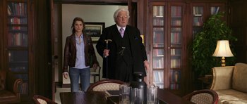 Movie still from “Bedtime Stories” (2008), directed by Adam Shankman – An older man and a young woman standing in front of a dining room table; Medium shot, Low angle