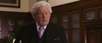 Movie still from “Bedtime Stories” (2008), directed by Adam Shankman – An older man in a black suit and purple tie; Close Up shot, Over the shoulder angle