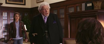 Movie still from “Bedtime Stories” (2008), directed by Adam Shankman – An older man in a black suit and purple tie; Medium shot, Over the shoulder angle