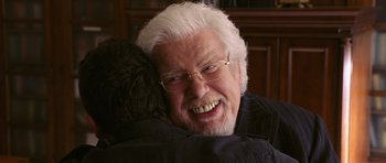 Movie still from “Bedtime Stories” (2008), directed by Adam Shankman – An older man with white hair is smiling for the camera; Close Up shot, Over the shoulder angle
