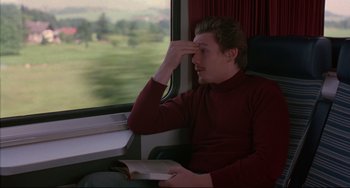 Movie still from “Before Sunrise” (1995), directed by Richard Linklater – A man sitting on a train holding a book; Medium shot, High angle