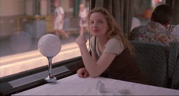 Movie still from “Before Sunrise” (1995), directed by Richard Linklater – A woman sitting at a table in front of a window; Medium shot, Over the shoulder angle