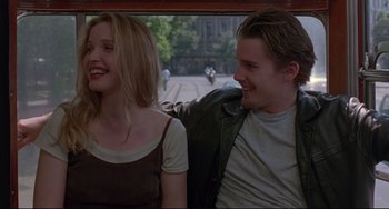 Movie still from “Before Sunrise” (1995), directed by Richard Linklater – A man and a woman sitting next to each other on a train; Medium shot, Over the shoulder angle