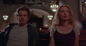 Movie still from “Before Sunrise” (1995), directed by Richard Linklater – A man and a woman sitting next to each other in front of lights; Medium shot, Low angle