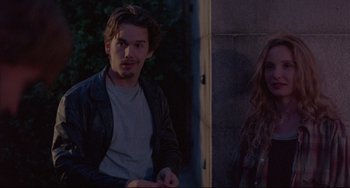 Movie still from “Before Sunrise” (1995), directed by Richard Linklater – A man and a woman sitting next to each other in front of a building; Medium shot, Over the shoulder angle