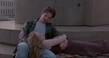 Movie still from “Before Sunrise” (1995), directed by Richard Linklater – A man and a woman sitting next to each other on the ground; Medium shot, Over the shoulder angle