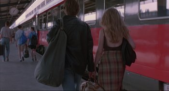 Movie still from “Before Sunrise” (1995), directed by Richard Linklater – A man and a woman walking on a train platform holding hands; Wide shot, Low angle