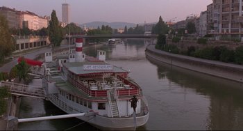 Movie still from “Before Sunrise” (1995), directed by Richard Linklater – A boat is in the water near a bridge; Extreme Wide shot, High angle
