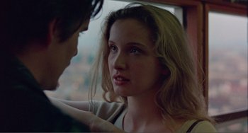 Movie still from “Before Sunset” (2004), directed by Richard Linklater – A young woman looking at the camera while a man holds her hand; Close Up shot, Over the shoulder angle