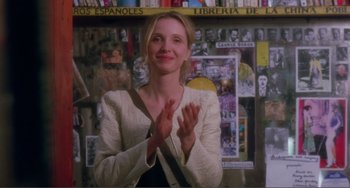 Movie still from “Before Sunset” (2004), directed by Richard Linklater – A woman clapping her hands in front of a wall covered in posters; Medium shot, Over the shoulder angle
