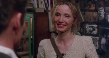 Movie still from “Before Sunset” (2004), directed by Richard Linklater – A woman smiling for the camera in front of a bookshelf; Close Up shot, Over the shoulder angle