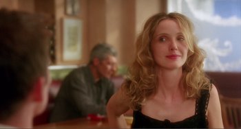 Movie still from “Before Sunset” (2004), directed by Richard Linklater – A woman sitting at a table with a man in the background; Close Up shot, Over the shoulder angle
