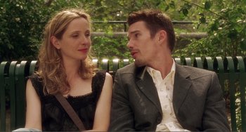 Movie still from “Before Sunset” (2004), directed by Richard Linklater – A man and a woman sitting next to each other on a park bench; Medium shot, Low angle