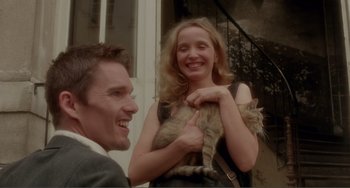 Movie still from “Before Sunset” (2004), directed by Richard Linklater – A man and woman holding a cat in front of a building; Medium shot, Low angle