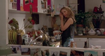 Movie still from “Before Sunset” (2004), directed by Richard Linklater – A woman standing in a cluttered kitchen holding her hand to her face; Medium shot, Over the shoulder angle