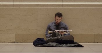 Movie still from “Before We Go” (2014), directed by Chris Evans – A man sitting on the ground holding a trumpet; Wide shot, Low angle