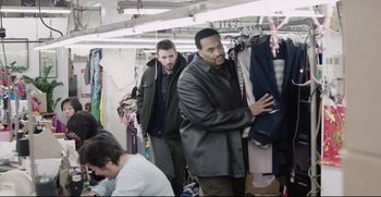 Movie still from “Before We Go” (2014), directed by Chris Evans – A group of people in a room looking at clothes on hangers; Medium shot, Over the shoulder angle