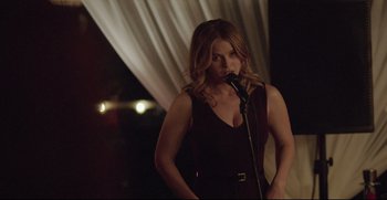 Movie still from “Before We Go” (2014), directed by Chris Evans – A woman in a black dress holding a microphone; Medium shot, Over the shoulder angle