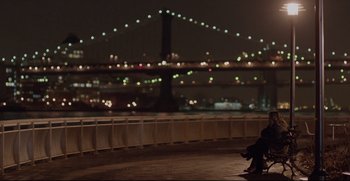 Movie still from “Before We Go” (2014), directed by Chris Evans – A man sitting on a bench in front of a bridge; Wide shot, Over the shoulder angle